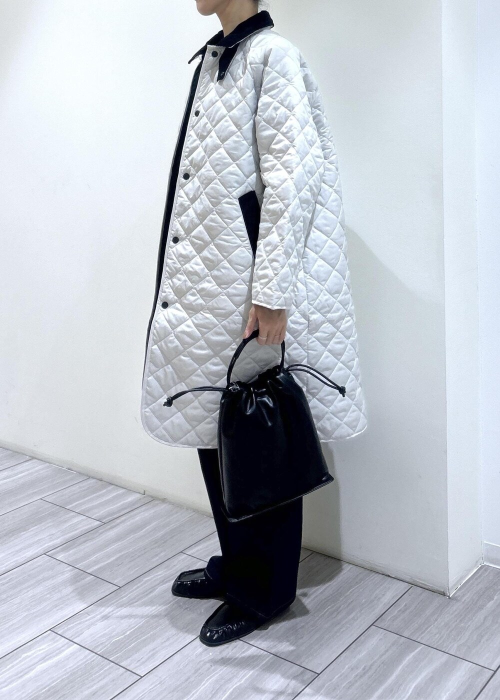 ホワイト系のナイロンジャケット、ブラック系のデニムパンツ、ブラウン系のローファーを着用したレディースの秋コーディネートの3枚目の写真