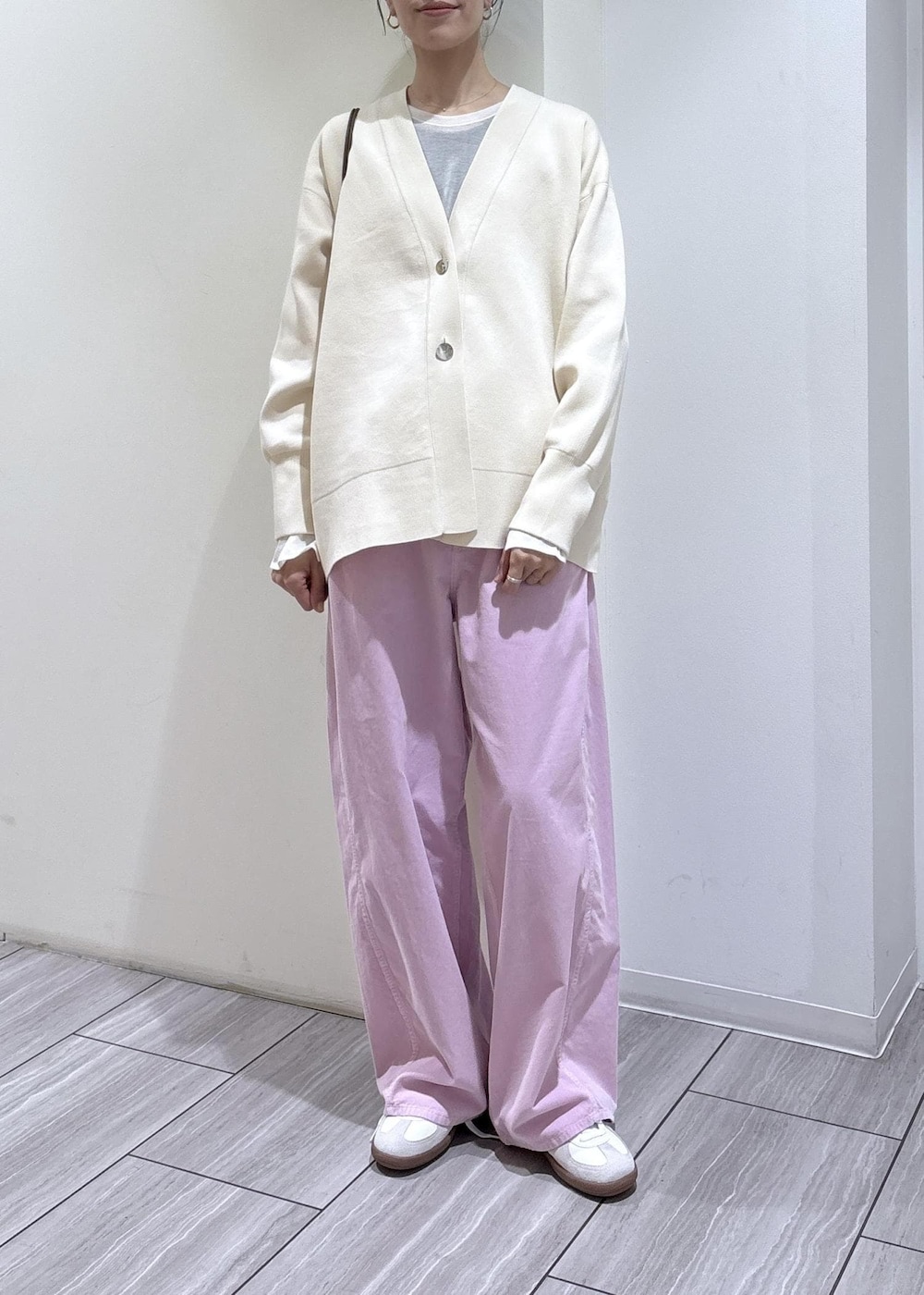 ホワイト系のスニーカー、ホワイト系のカーディガン/ボレロ、ブラウン系のショルダーバッグを着用したレディースの冬コーディネートの2枚目の写真