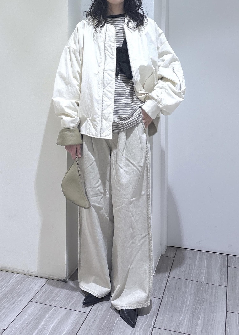 ブラック系のパンプス、ブラック系のベスト、ホワイト系のMA-1を着用したレディースの冬コーディネートの5枚目の写真