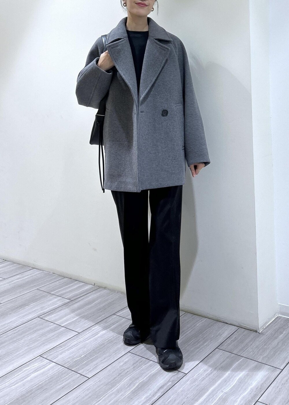 ブラック系のスウェット、ブラック系のショルダーバッグ、グレー系のステンカラーコートを着用したレディースの秋コーディネートの7枚目の写真