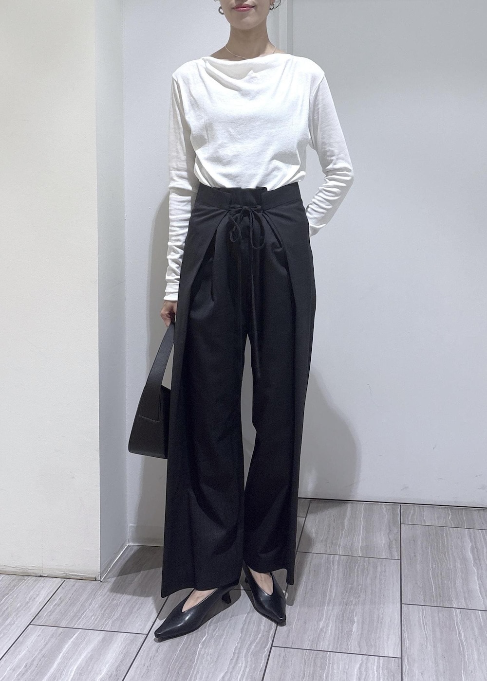 ブラック系のショルダーバッグ、ブラック系のパンプス、ホワイト系のTシャツ/カットソーを着用したレディースの夏コーディネートの2枚目の写真