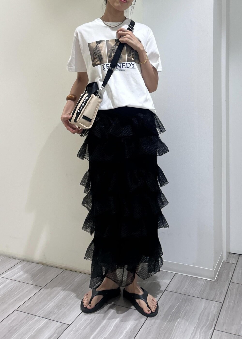 ブラック系のサンダル、ホワイト系のTシャツ/カットソー、ブラック系のスカートを着用したレディースの夏コーディネートの4枚目の写真