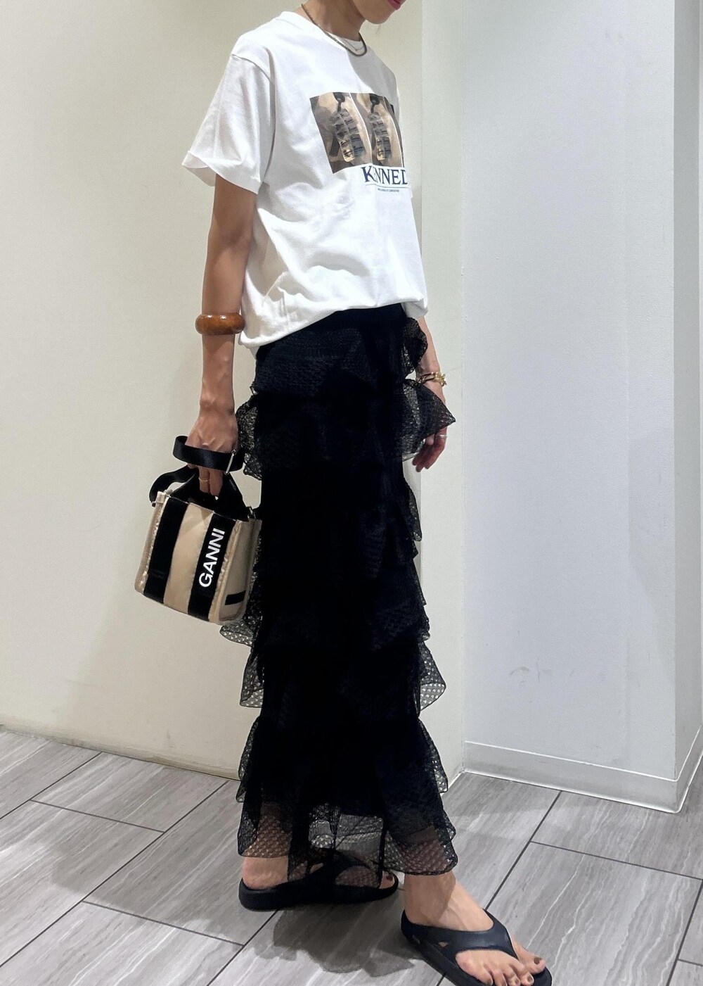 ブラック系のサンダル、ホワイト系のTシャツ/カットソー、ブラック系のスカートを着用したレディースの夏コーディネートの3枚目の写真