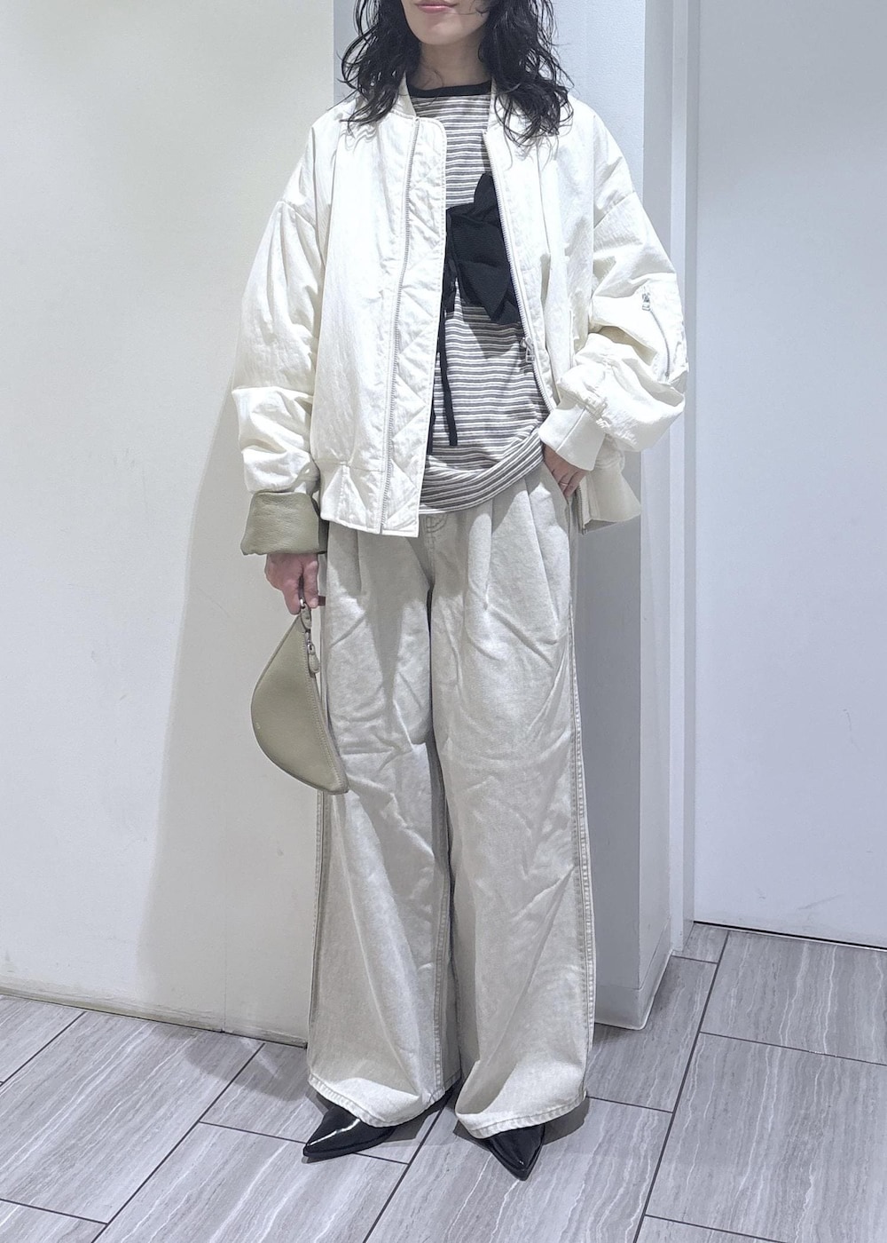 ブラック系のパンプス、ブラック系のベスト、ホワイト系のMA-1を着用したレディースの冬コーディネートの4枚目の写真