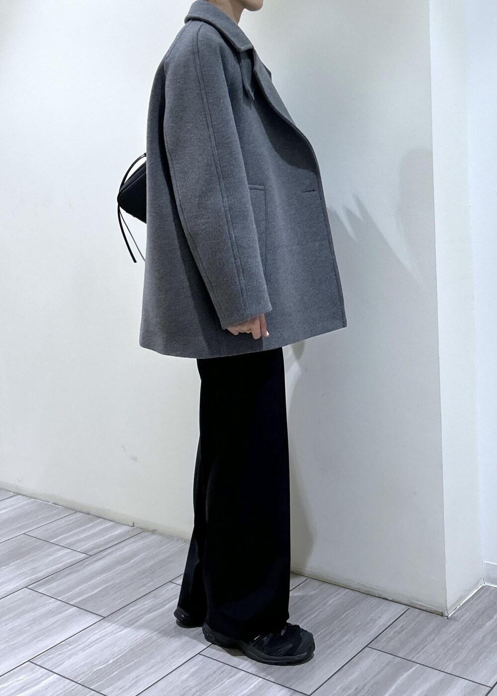 ブラック系のスウェット、ブラック系のショルダーバッグ、グレー系のステンカラーコートを着用したレディースの秋コーディネートの6枚目の写真