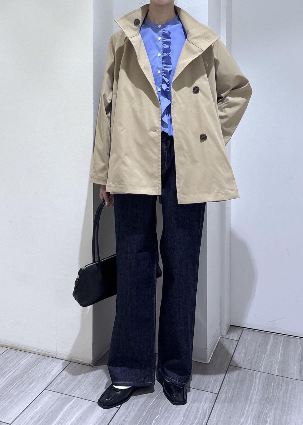 ブラック系のバレエシューズ、ブラック系のボストンバッグ、ベージュ系のトレンチコートを着用したレディースの春コーディネートの2枚目の写真