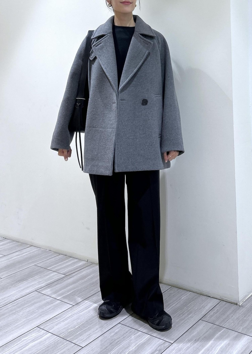ブラック系のスウェット、ブラック系のショルダーバッグ、グレー系のステンカラーコートを着用したレディースの秋コーディネートの2枚目の写真