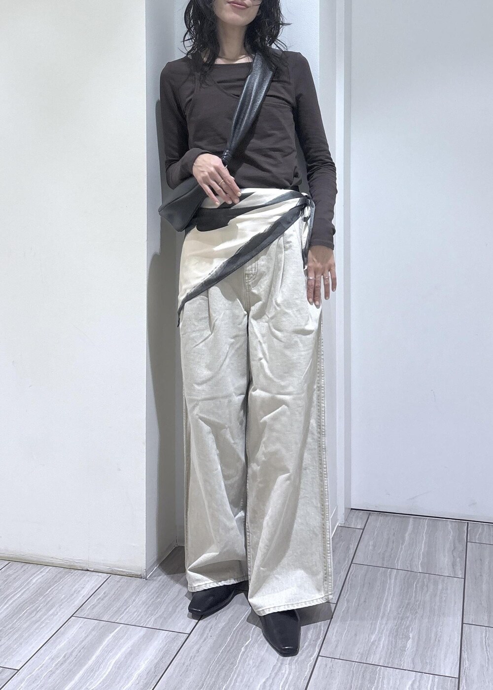 ブラウン系のTシャツ/カットソー、ブラック系のサンダル、ベージュ系のデニムパンツを着用したレディースの冬コーディネートの5枚目の写真