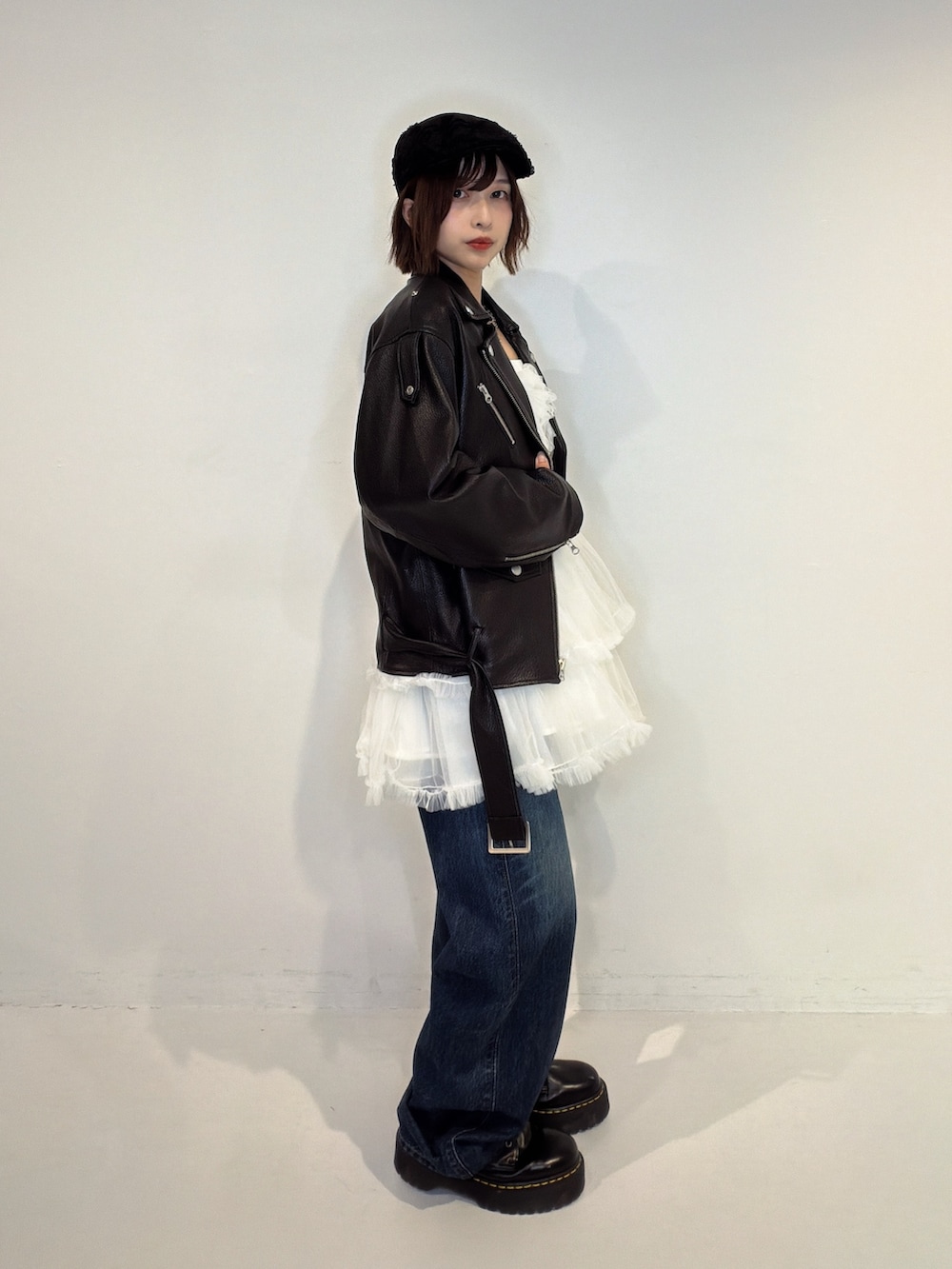 ブルー系のデニムパンツ、ホワイト系のワンピース、ブラック系のライダースジャケットを着用したレディースの秋コーディネートの2枚目の写真