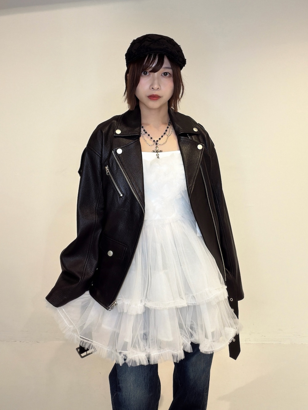 ブルー系のデニムパンツ、ホワイト系のワンピース、ブラック系のライダースジャケットを着用したレディースの秋コーディネートの6枚目の写真