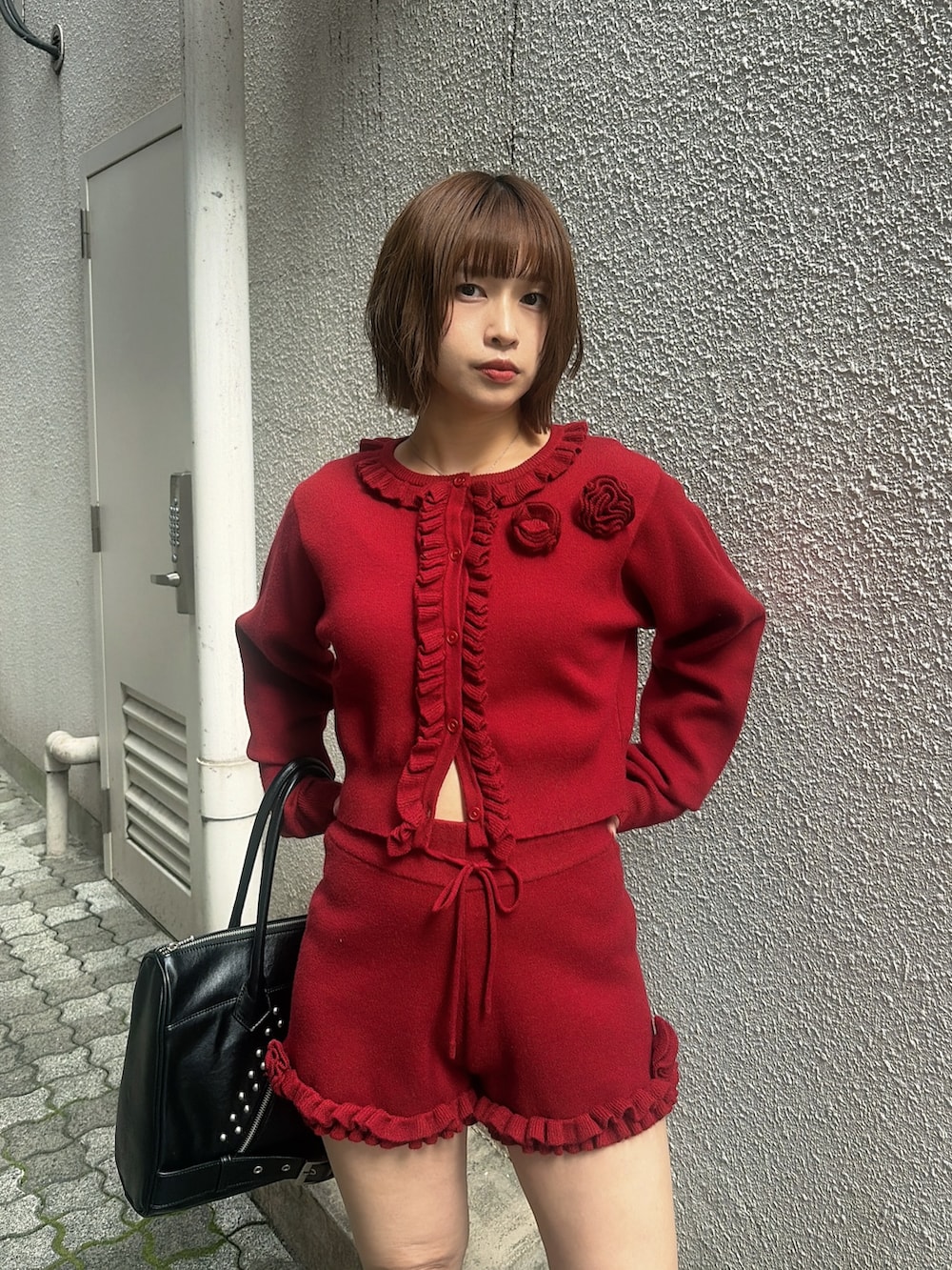 レッド系のカーディガン/ボレロ、レッド系のその他パンツ、ブラック系のハンドバッグを着用したレディースの秋コーディネートの6枚目の写真