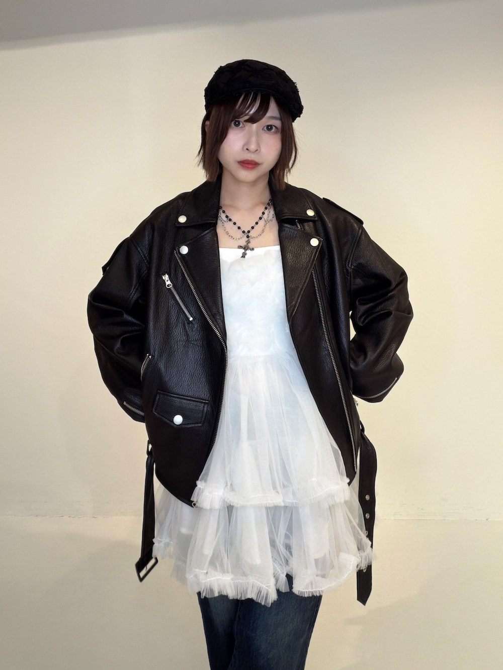 ブルー系のデニムパンツ、ホワイト系のワンピース、ブラック系のライダースジャケットを着用したレディースの秋コーディネートの5枚目の写真