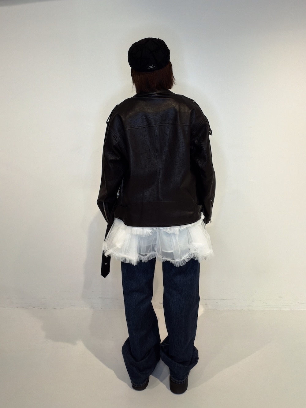 ブルー系のデニムパンツ、ホワイト系のワンピース、ブラック系のライダースジャケットを着用したレディースの秋コーディネートの3枚目の写真