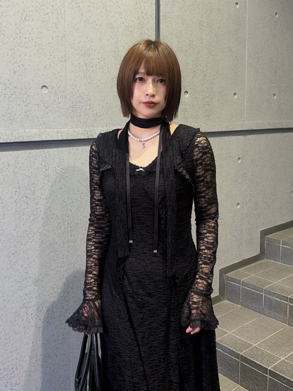 ブラック系のブーツ、ブラック系のハンドバッグ、ブラック系のワンピースを着用したレディースの秋コーディネートの5枚目の写真