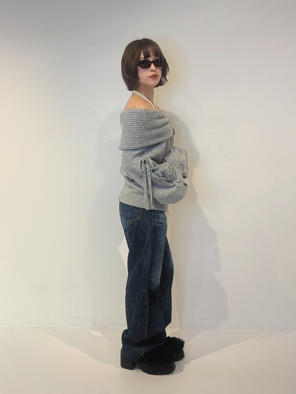 ブルー系のデニムパンツ、ブラック系のサンダル、グレー系のニット/セーターを着用したレディースの秋コーディネートの2枚目の写真