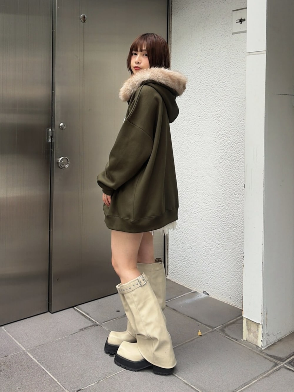ホワイト系のスカート、ベージュ系のTシャツ/カットソー、ホワイト系のブーツを着用したレディースの秋コーディネートの2枚目の写真