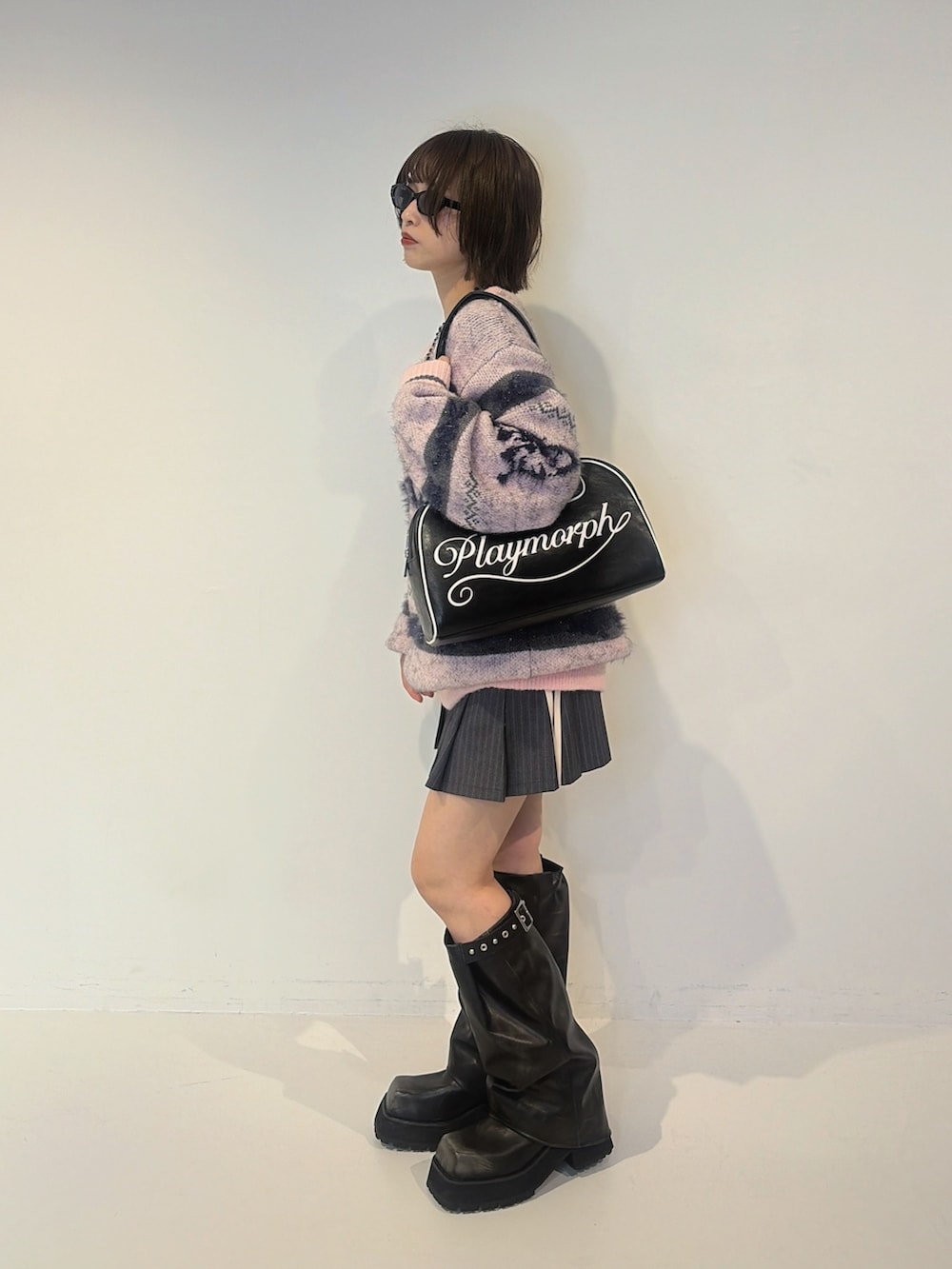 グレー系のスカート、ピンク系のニット/セーター、ブラック系のボストンバッグを着用したレディースの夏コーディネートの2枚目の写真