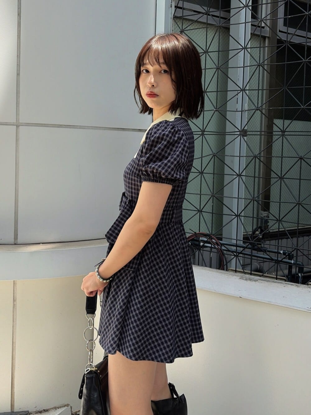 ブルー系のワンピース、ブラック系のハンドバッグ、ブラック系のブーツを着用したレディースの夏コーディネートの4枚目の写真