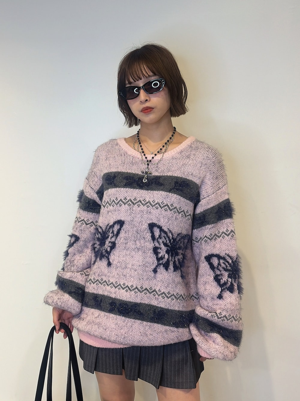 グレー系のスカート、ピンク系のニット/セーター、ブラック系のボストンバッグを着用したレディースの夏コーディネートの5枚目の写真