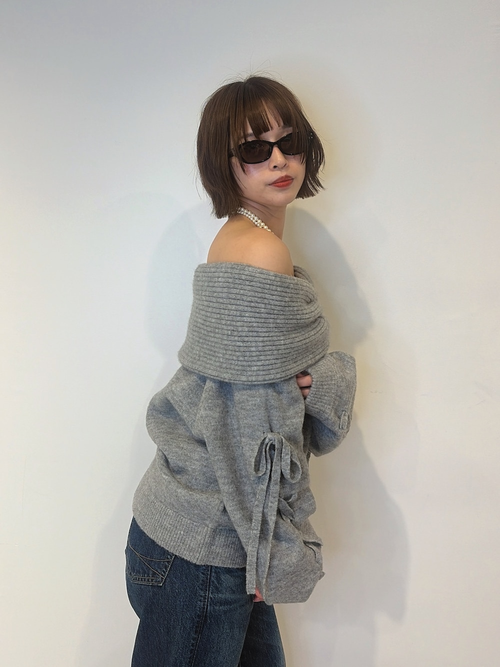 ブルー系のデニムパンツ、ブラック系のサンダル、グレー系のニット/セーターを着用したレディースの秋コーディネートの6枚目の写真