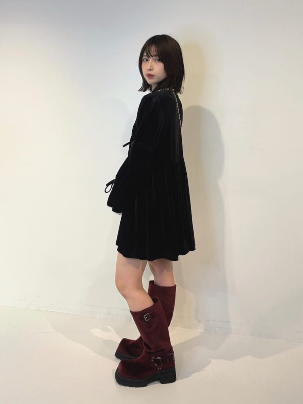 ブラック系のワンピース、グレー系のハンドバッグ、レッド系のブーツを着用したレディースの夏コーディネートの2枚目の写真