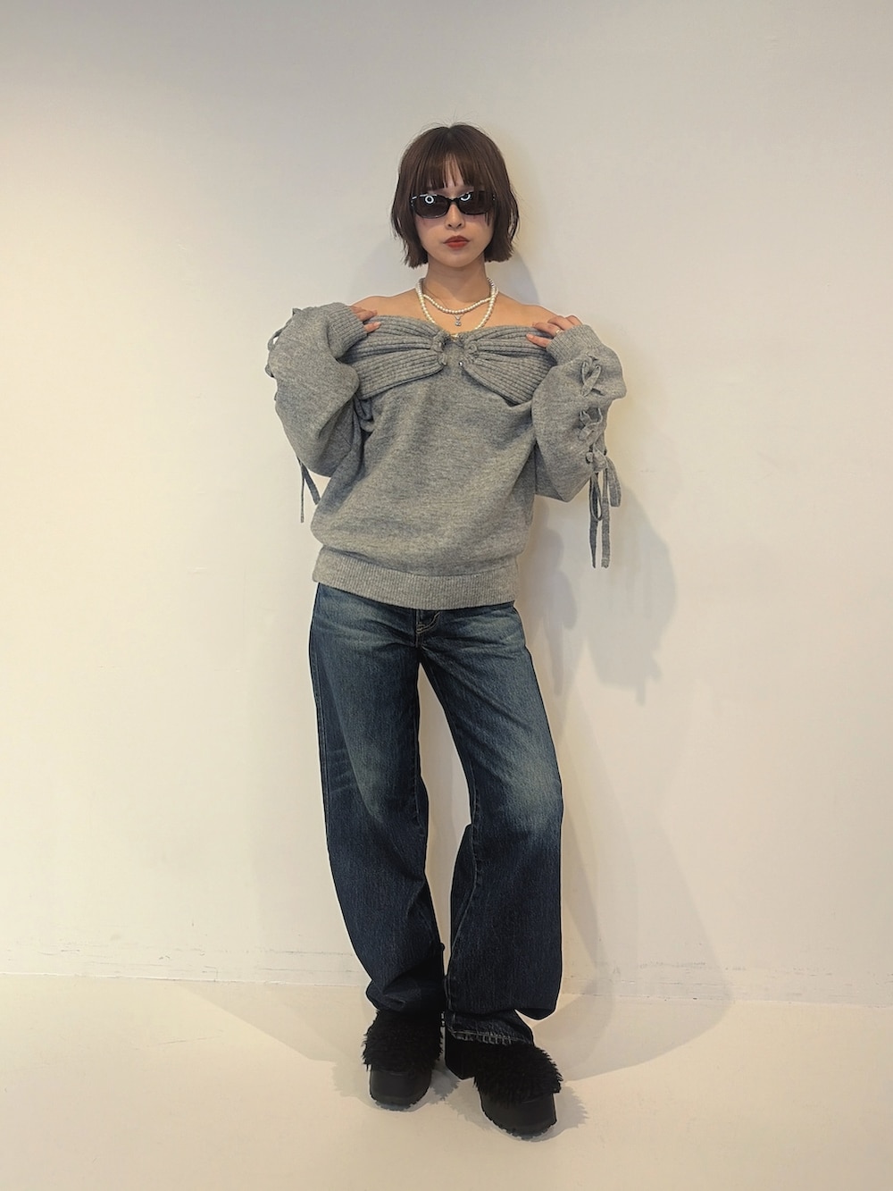 ブルー系のデニムパンツ、ブラック系のサンダル、グレー系のニット/セーターを着用したレディースの秋コーディネートの4枚目の写真