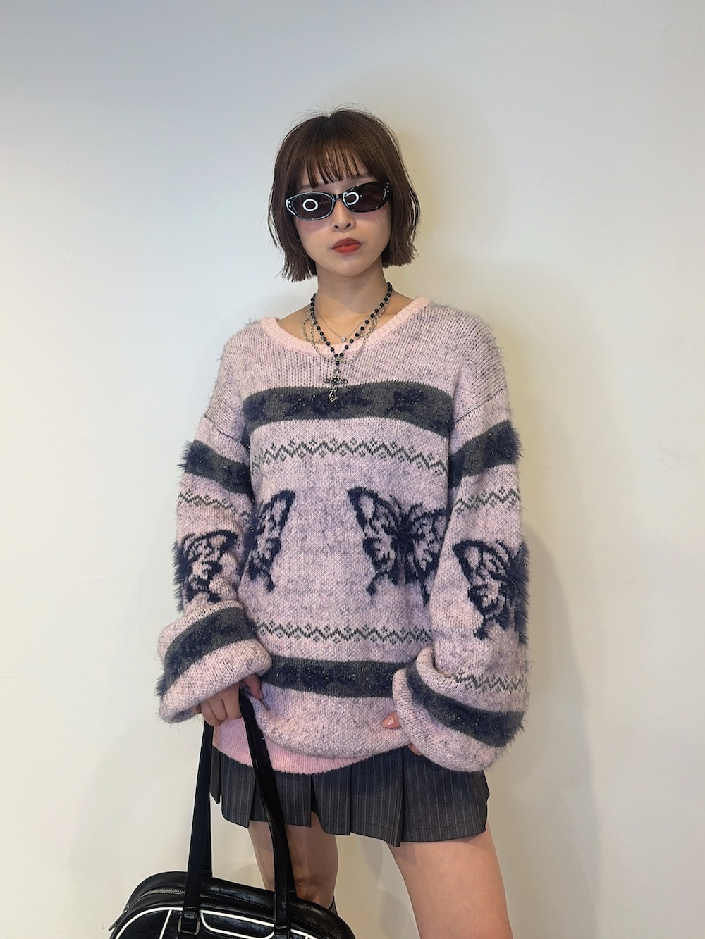 グレー系のスカート、ピンク系のニット/セーター、ブラック系のボストンバッグを着用したレディースの夏コーディネートの4枚目の写真