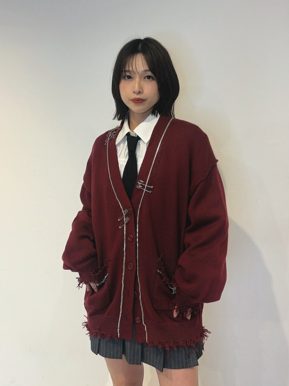 レッド系のカーディガン/ボレロ、ホワイト系のシャツ/ブラウス、グレー系のスカートを着用したレディースの夏コーディネートの4枚目の写真