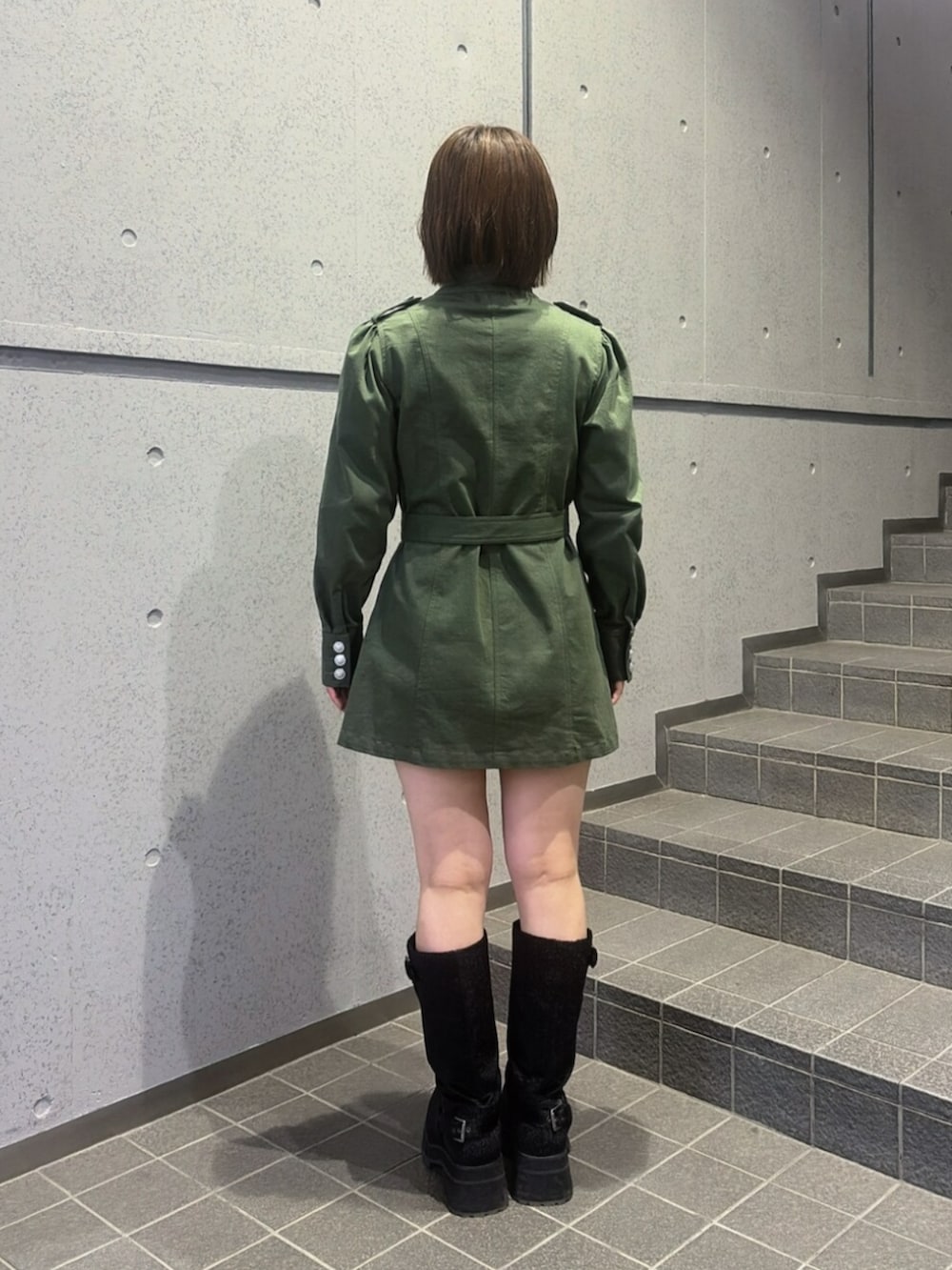 グリーン系のワンピース、ブラック系のブーツを着用したレディースの秋コーディネートの3枚目の写真