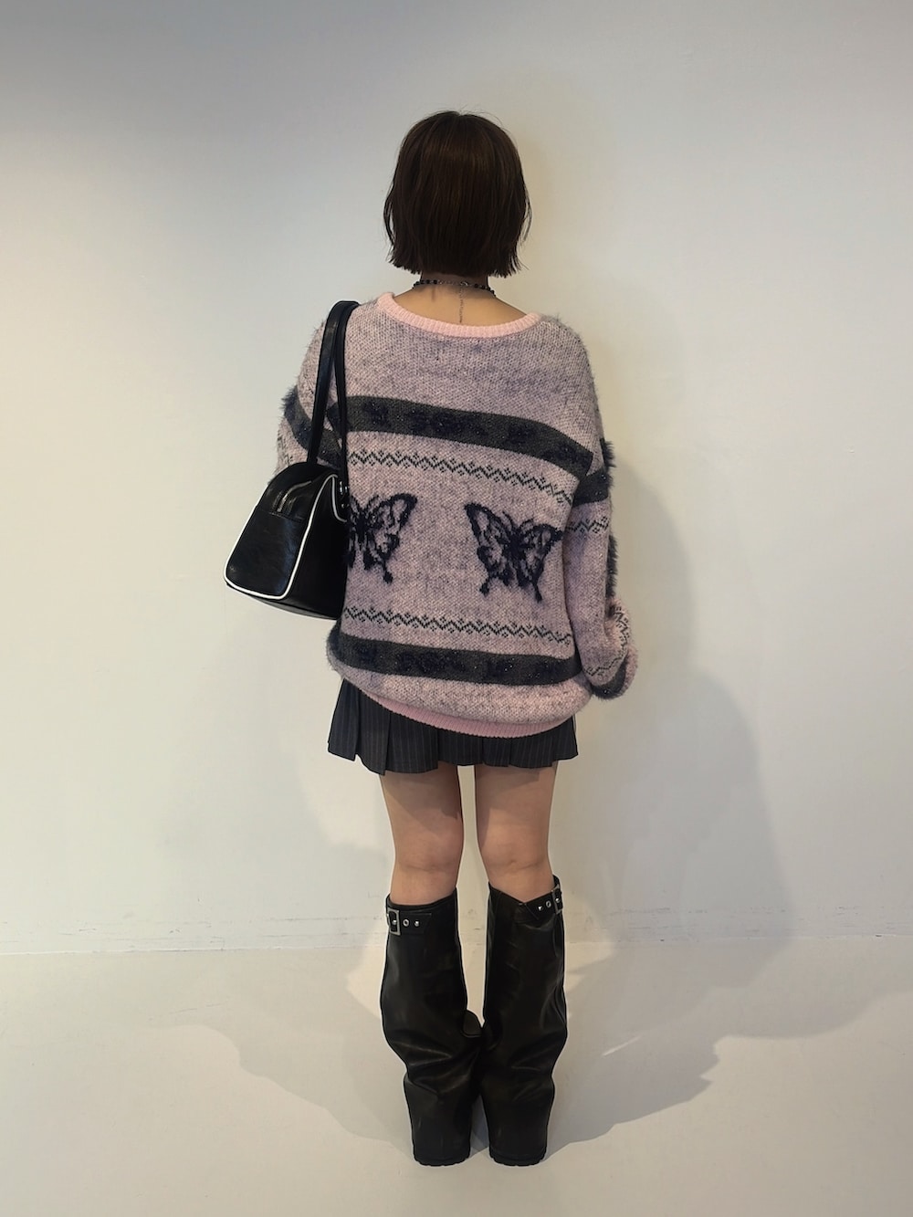 グレー系のスカート、ピンク系のニット/セーター、ブラック系のボストンバッグを着用したレディースの夏コーディネートの3枚目の写真