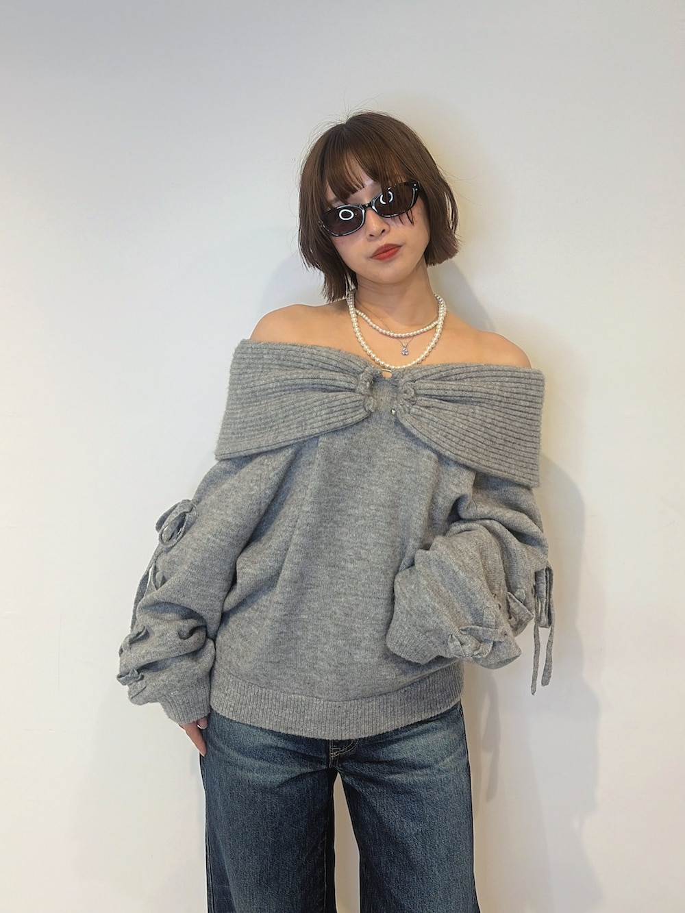 ブルー系のデニムパンツ、ブラック系のサンダル、グレー系のニット/セーターを着用したレディースの秋コーディネートの5枚目の写真