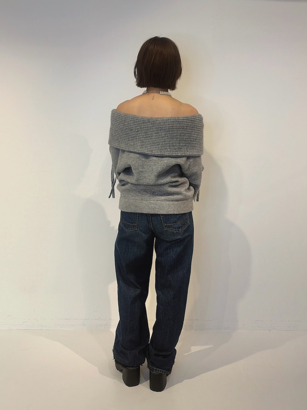 ブルー系のデニムパンツ、ブラック系のサンダル、グレー系のニット/セーターを着用したレディースの秋コーディネートの3枚目の写真