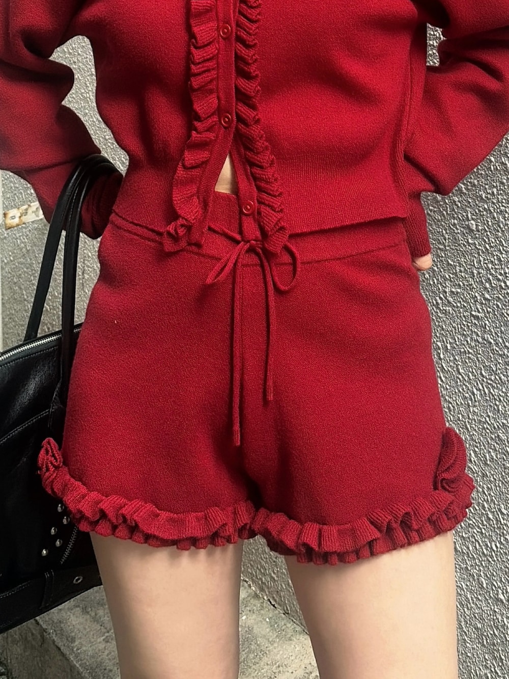 レッド系のカーディガン/ボレロ、レッド系のその他パンツ、ブラック系のハンドバッグを着用したレディースの秋コーディネートの4枚目の写真