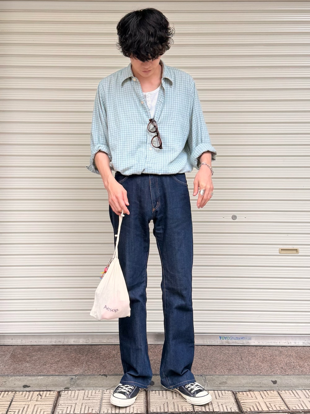 ベージュ系のタンクトップ、ブルー系のデニムパンツ、ブラック系のスニーカーを着用したメンズの夏コーディネートの3枚目の写真