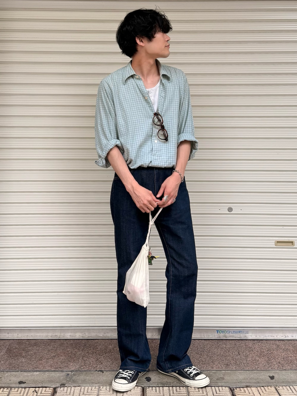 ベージュ系のタンクトップ、ブルー系のデニムパンツ、ブラック系のスニーカーを着用したメンズの夏コーディネートの2枚目の写真