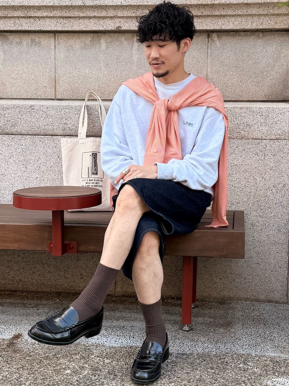 グレー系のスウェット、ブルー系のデニムパンツ、ブラック系のローファーを着用したメンズの秋コーディネートの2枚目の写真