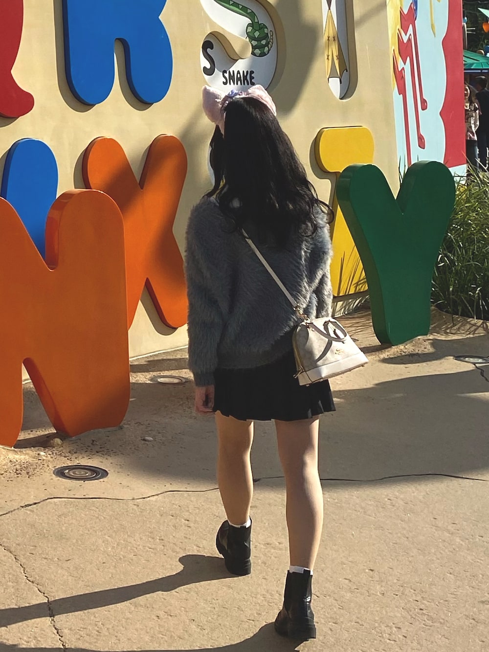 グレー系のカーディガン/ボレロ、ブラック系のスカート、ブラック系のブーツを着用したレディースの春コーディネートの2枚目の写真