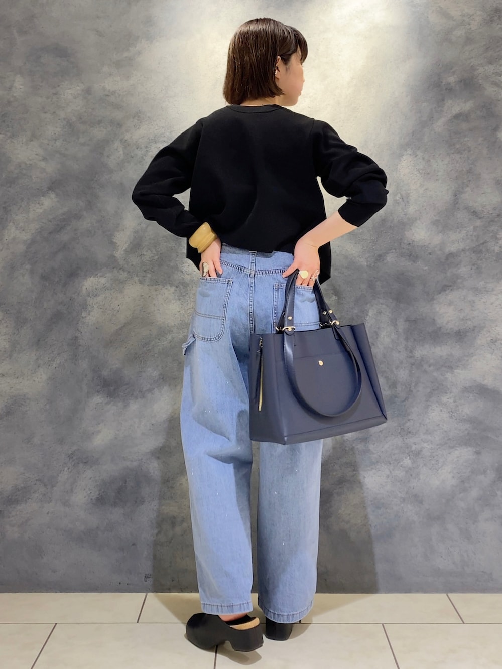 ブルー系のデニムパンツ、ブルー系のトートバッグ、ブラック系のサンダルを着用したレディースの冬コーディネートの3枚目の写真