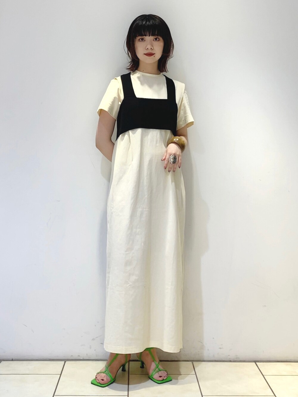 ホワイト系のワンピース、グリーン系のハンドバッグ、オレンジ系のサンダルを着用したレディースの夏コーディネートの2枚目の写真