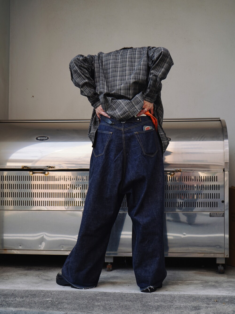 オレンジ系のTシャツ/カットソー、ブラウン系のシャツ/ブラウス、ブルー系のデニムパンツを着用したメンズの春コーディネートの5枚目の写真