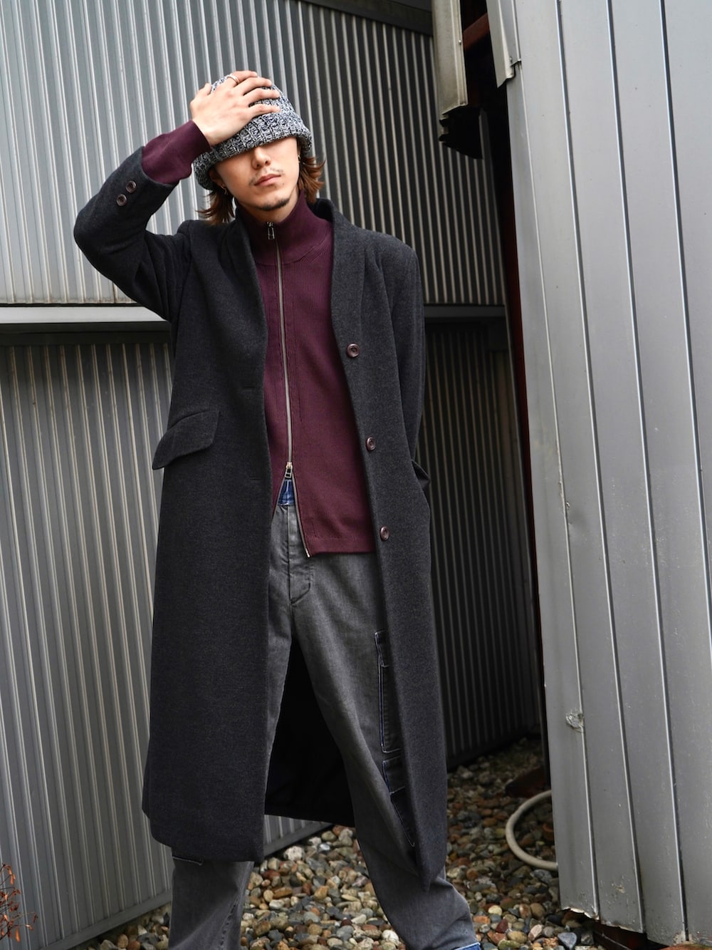 レッド系のニット/セーター、グレー系のノーカラーコート、ブラック系のデニムパンツを着用したメンズの秋コーディネートの4枚目の写真