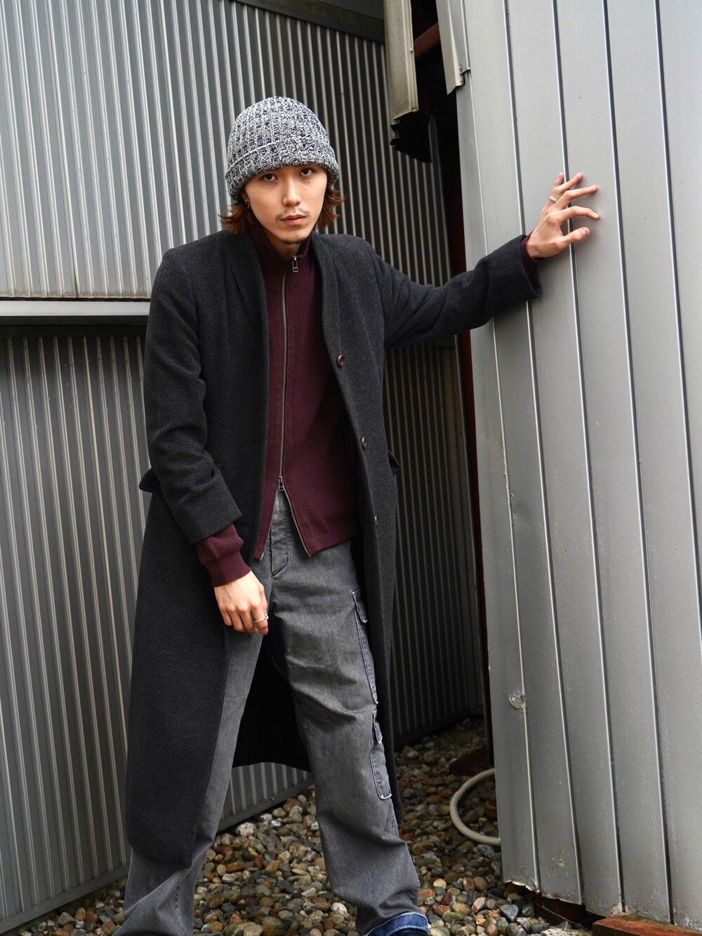 レッド系のニット/セーター、グレー系のノーカラーコート、ブラック系のデニムパンツを着用したメンズの秋コーディネートの3枚目の写真