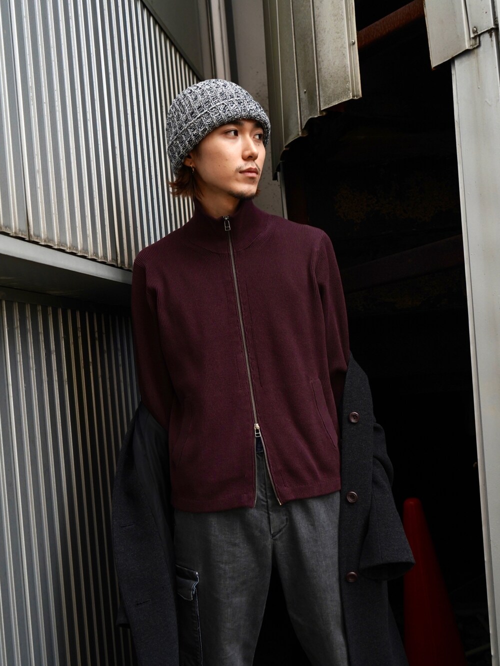 レッド系のニット/セーター、グレー系のノーカラーコート、ブラック系のデニムパンツを着用したメンズの秋コーディネートの5枚目の写真