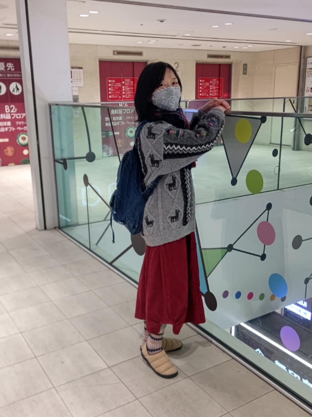 ベージュ系のスリッポン、レッド系のスカート、グレー系のその他アウターを着用したレディースの冬コーディネートの2枚目の写真