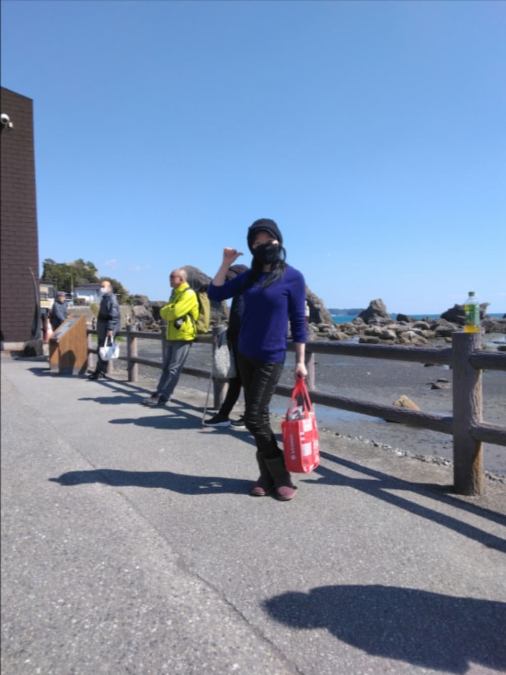 レッド系のバッグ、パープル系のブーツ、ブルー系のニット/セーターを着用したレディースの春コーディネートの2枚目の写真