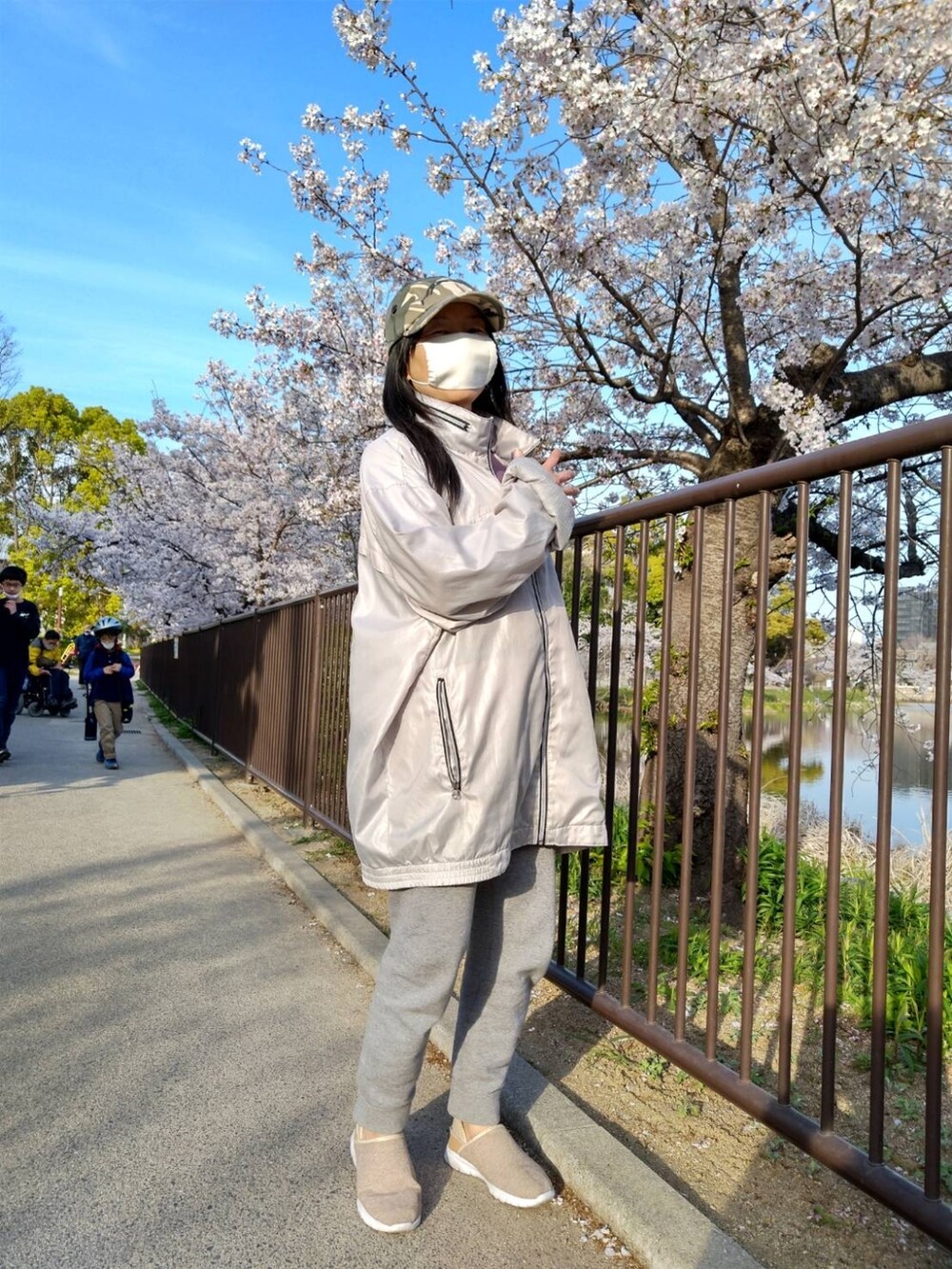 シルバー系のナイロンジャケット、グレー系のスウェットパンツ、パープル系のTシャツ/カットソーを着用したレディースの春コーディネートの2枚目の写真