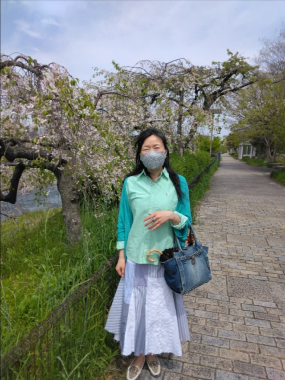 ブルー系のバッグ、ベージュ系のローファー、ブルー系のスカートを着用したレディースの春コーディネートの2枚目の写真