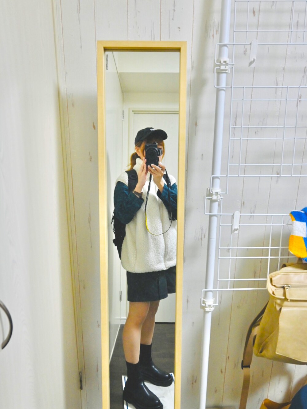 グリーン系のトートバッグ、ブラック系のブーツ、ブラック系のパンツを着用したレディースの冬コーディネートの2枚目の写真