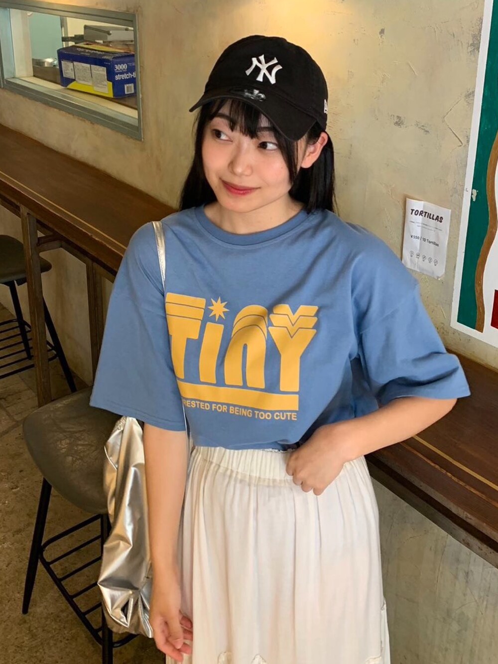 シルバー系のバックパック/リュック、ブルー系のTシャツ/カットソー、ホワイト系のスカートを着用したレディースの春コーディネートの2枚目の写真