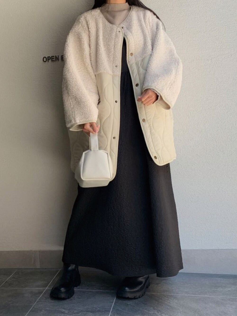 ホワイト系のショルダーバッグ、ブラック系のワンピース、ホワイト系のブルゾンを着用したレディースの秋コーディネートの2枚目の写真